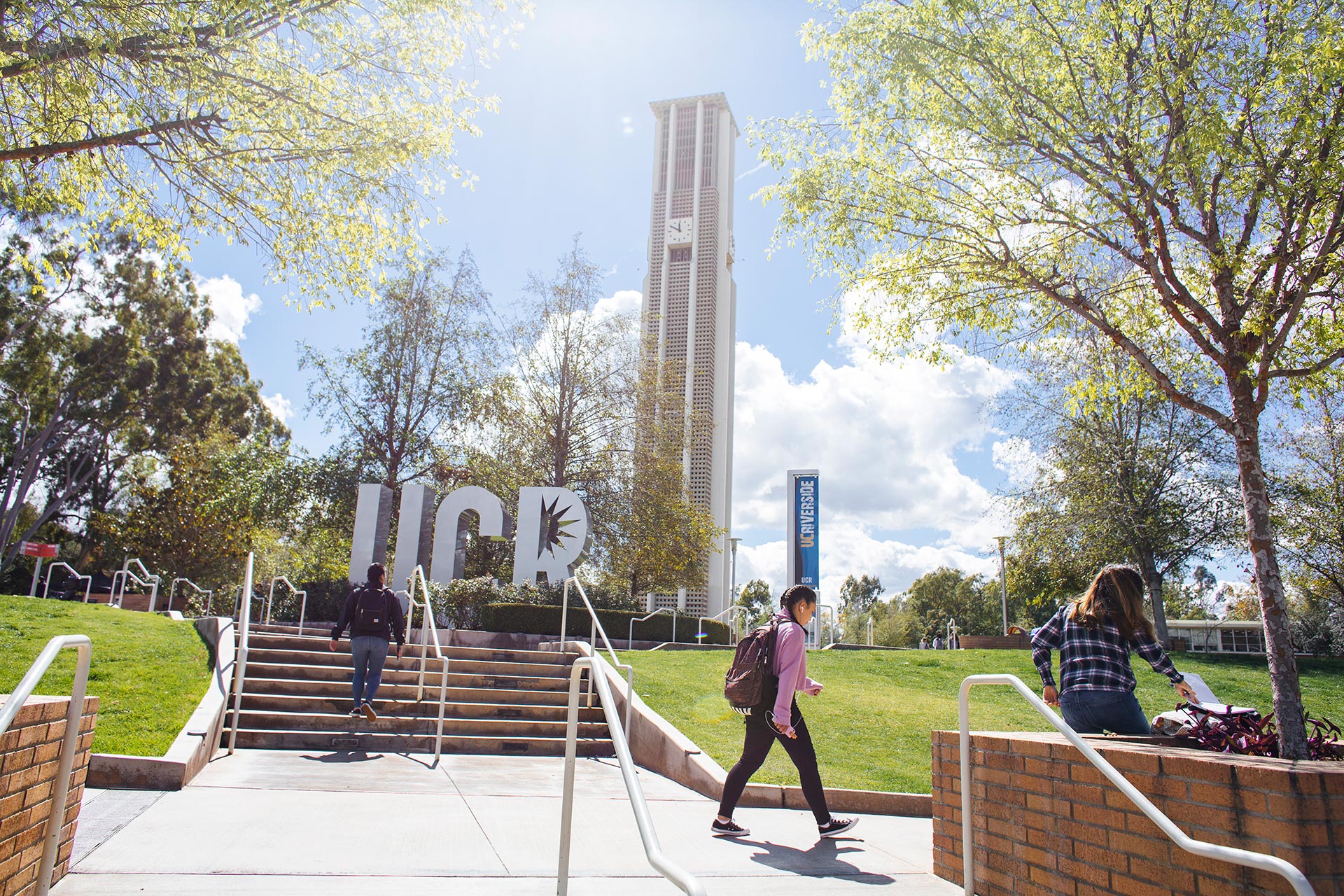 student walking past UCR sign and Bell Tower (c) Stan Lim